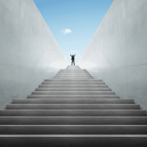 A person standing at the top of a long staircase with their arms raised